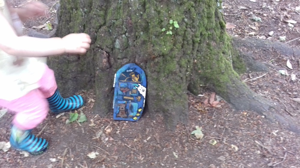 A blue painted fairy door on a tree amongst woo