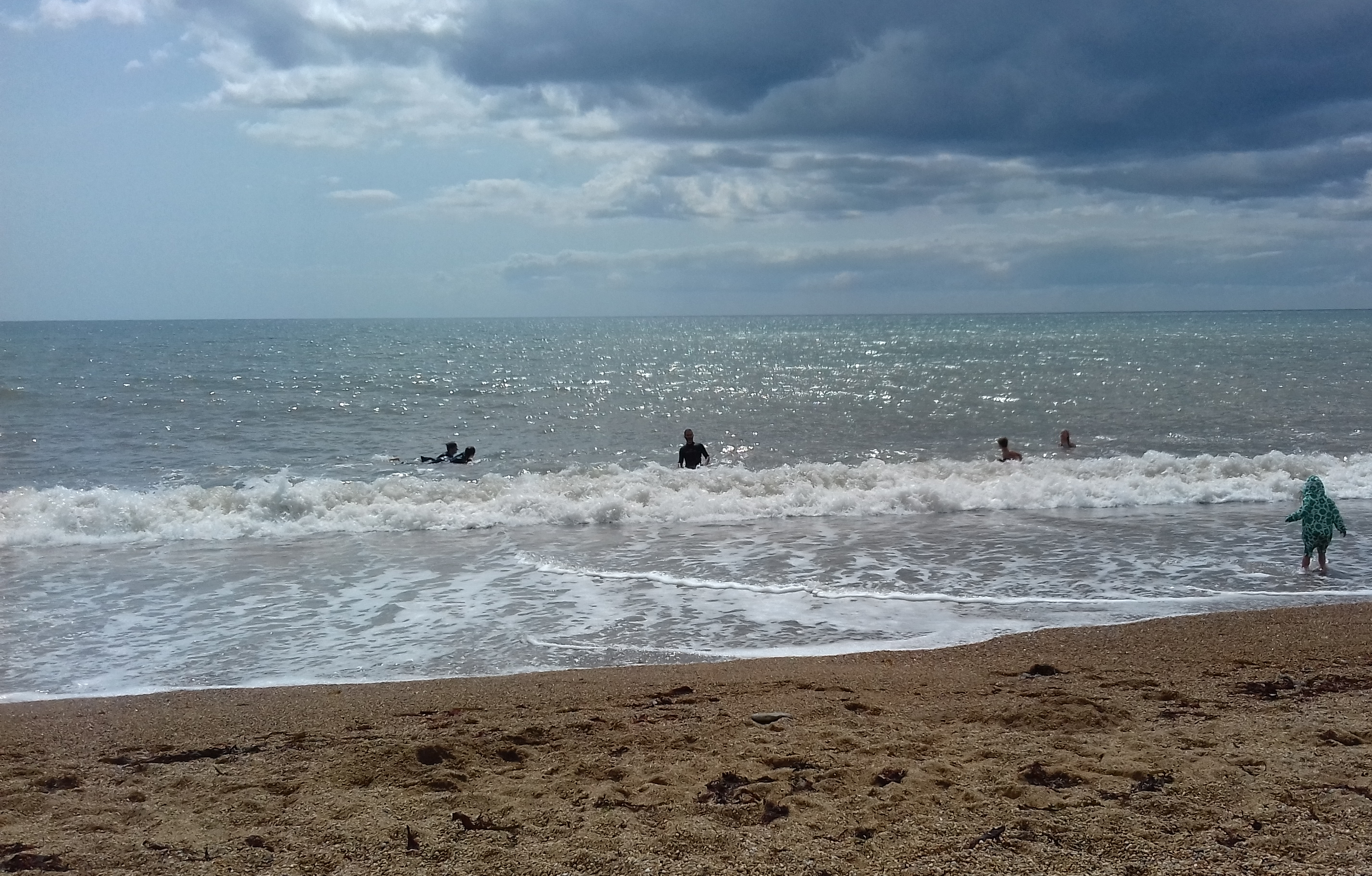 The sea and sand of Burton Bradstock with some paddlers