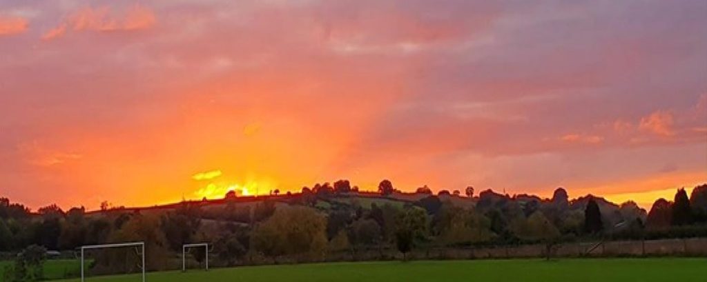Large field with goal posts and trees