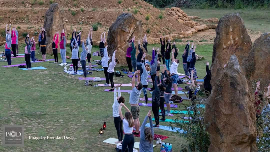 People with yoga mats in the outdoors stretching their hands to the sky