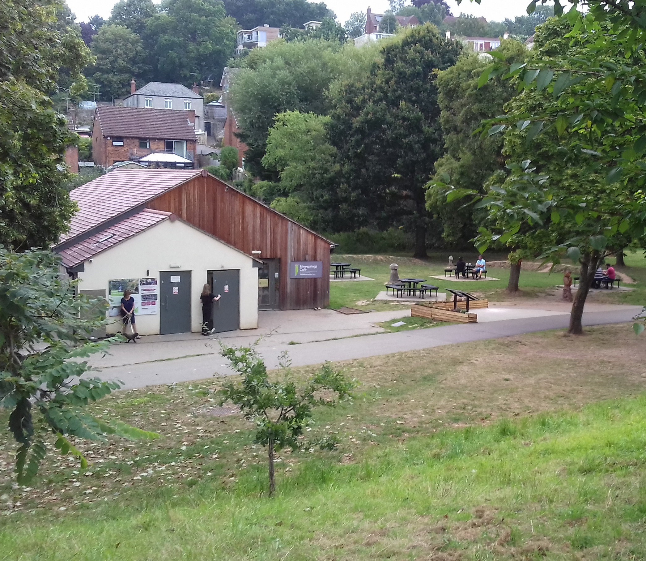 A wooden cafe structure with picnic benches outside set in woodland