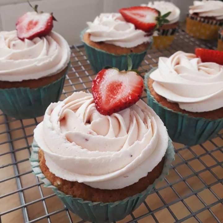 Cupcakes with fresh strawberries cooling on a wire rack
