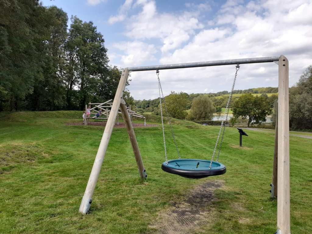 A large round swing and wooden climbing frame