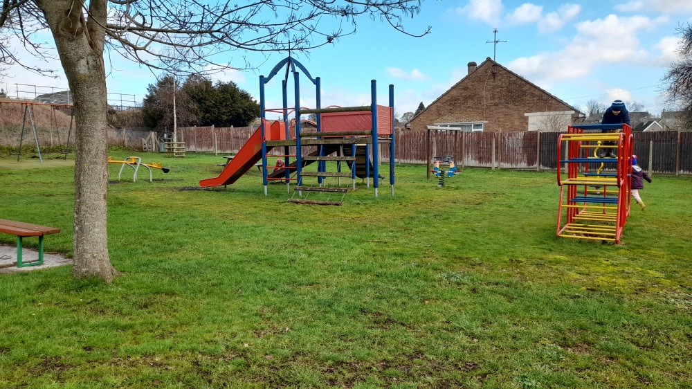 Primary coloured climbing frame with slide and another climbing frame too railway line just visible in the top left