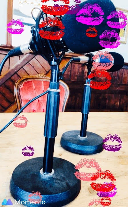 A couple of black microphones in stands on a table with lots of lipstick marks in different pink and purple hues all over the photo