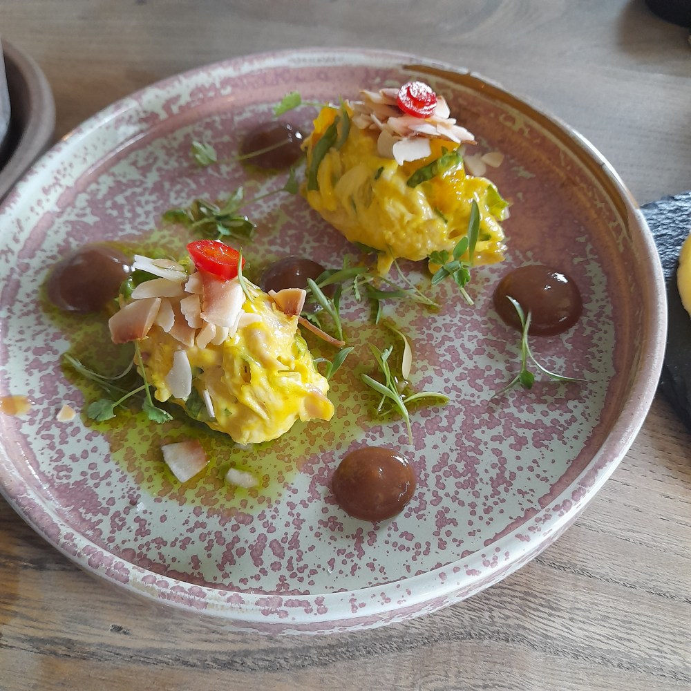 Pretty individual coronation chicken portions with herb and flower garnish