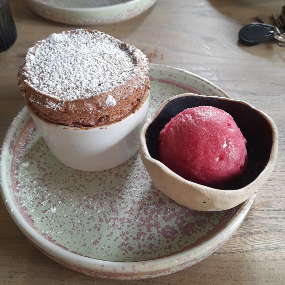 An individual berry soufflé with a scoop of bright berry sorbet